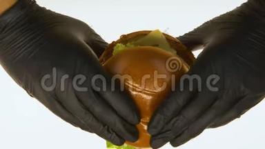 双手戴黑手套，品尝油腻的汉堡，控制垃圾食品质量